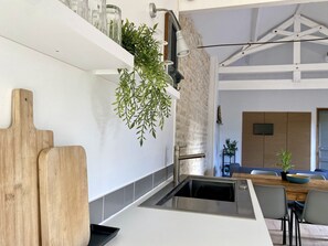 Eine moderne Küche mit eingebautem Spülbecken, einer hängenden Pflanze und einem Holztisch.