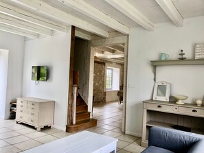 Una habitación con una escalera, un aparador blanco, un sofá azul y una estantería con adornos.