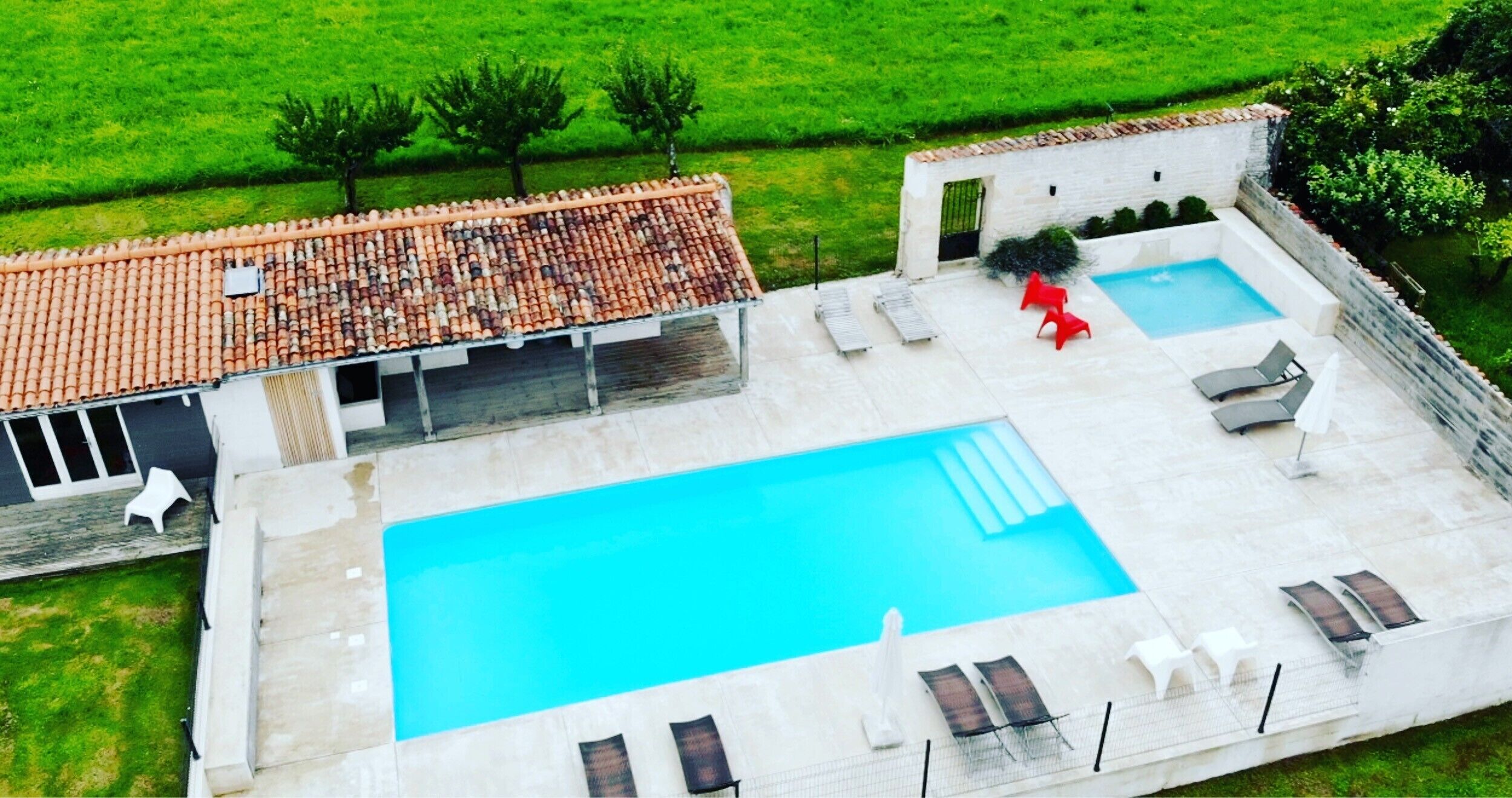 A rooftop pool with a tiled roof, a smaller pool, and lounge chairs.