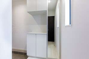 Een smalle gang met een witte kast en een donkere deur aan het einde.