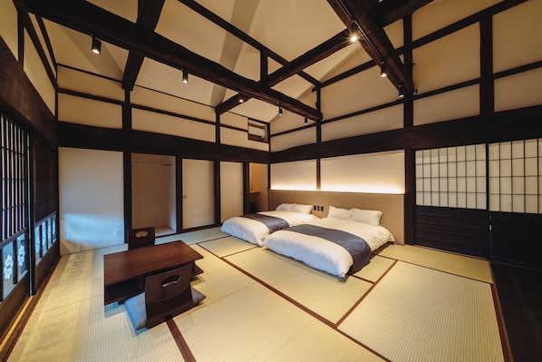Ein traditioneller japanischer Raum mit Tatami-Bodenbelag, einem niedrigen hölzernen Bett und einer Schiebetür.