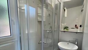 A modern bathroom with a glass-enclosed shower, a white sink, and a toilet.