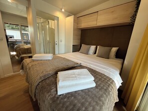 A hotel room with two beds, a large mirror, and a wooden headboard. - Mobile home LAMA 980 - Comfortable mobile home for up to 6 people (Biograd na Moru)