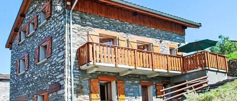 Un edificio de varios pisos de piedra con balcones de madera y una escalera que conduce al piso superior.