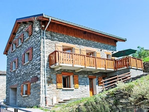 A multi-story stone building with wooden balconies and a staircase leading to the upper floor. - Balcon Cime de Caron by Interhome (Les Granges)