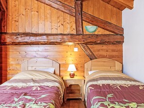 A cabin with two wooden beds, a nightstand with a lamp, and a rustic wooden ceiling. - Balcon Cime de Caron by Interhome (Les Granges)