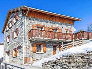 A stone building with wooden balconies and a snow-covered slope. - Balcon Cime de Caron by Interhome (Les Granges)