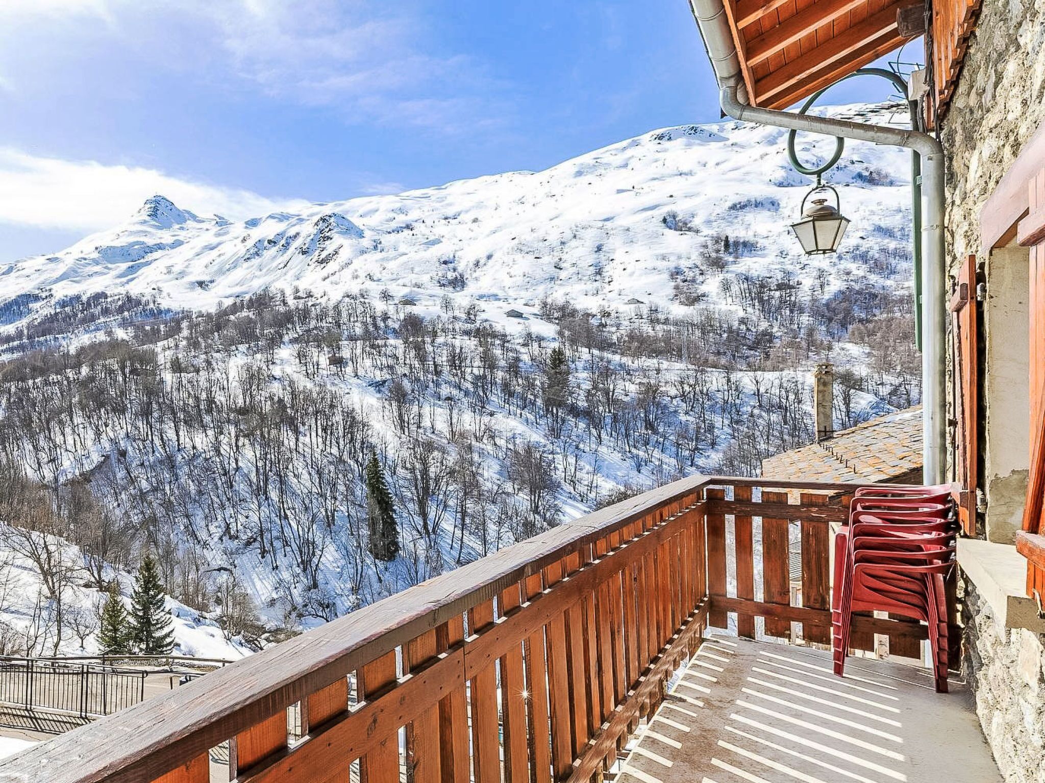 Un balcon doté d’une balustrade en bois, d’où l’on peut admirer un paysage montagneux enneigé.