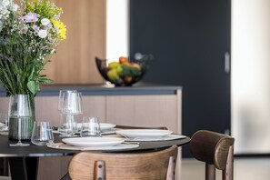A dining table set with plates, glasses, and a vase of flowers. - Villa Serenis – a Modern New-Build with Private Pool and Breathtaking Sea Views (Labin)