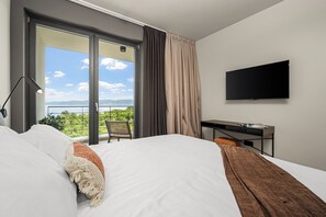 A hotel room with a bed, a desk, a TV, and a balcony with a view. - Villa Serenis – a Modern New-Build with Private Pool and Breathtaking Sea Views (Labin)
