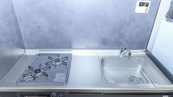 Uma cozinha compacta com fogão a gás, pia e forno embutido.