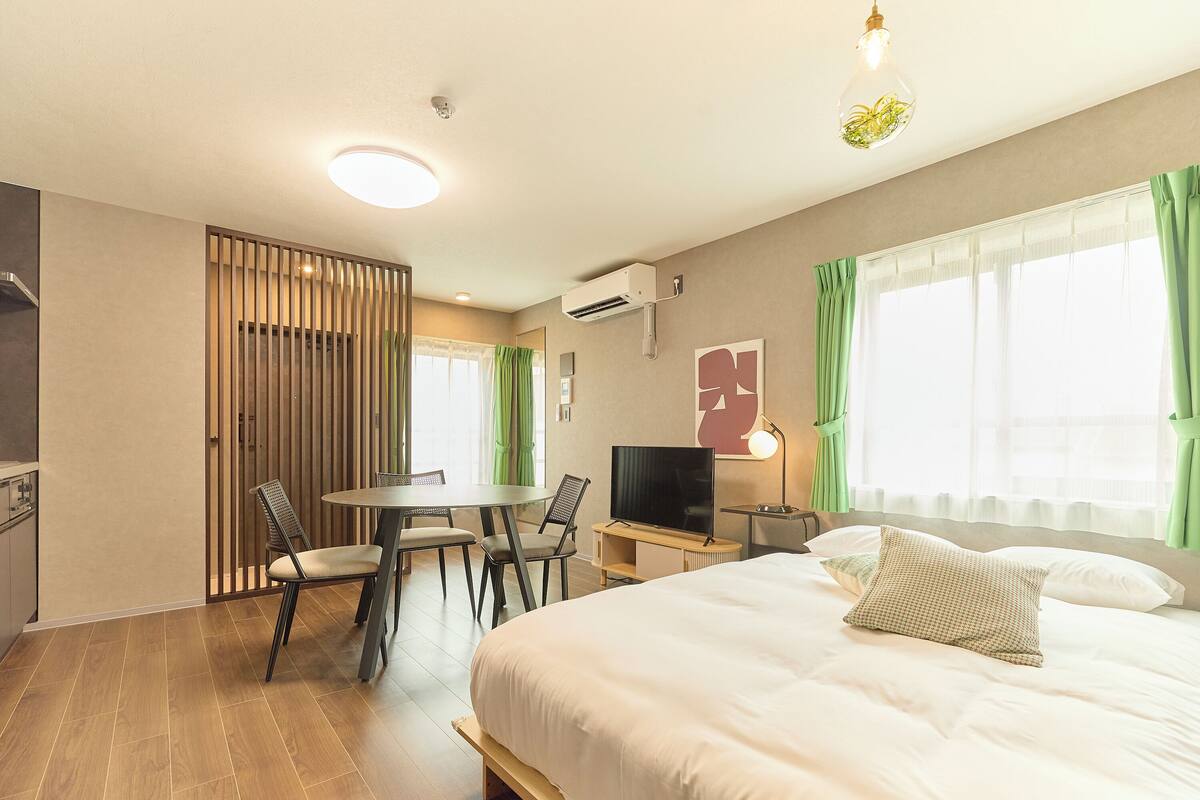 Une chambre d’hôtel avec un lit, un bureau et une chaise, une télévision et une fenêtre avec des rideaux.