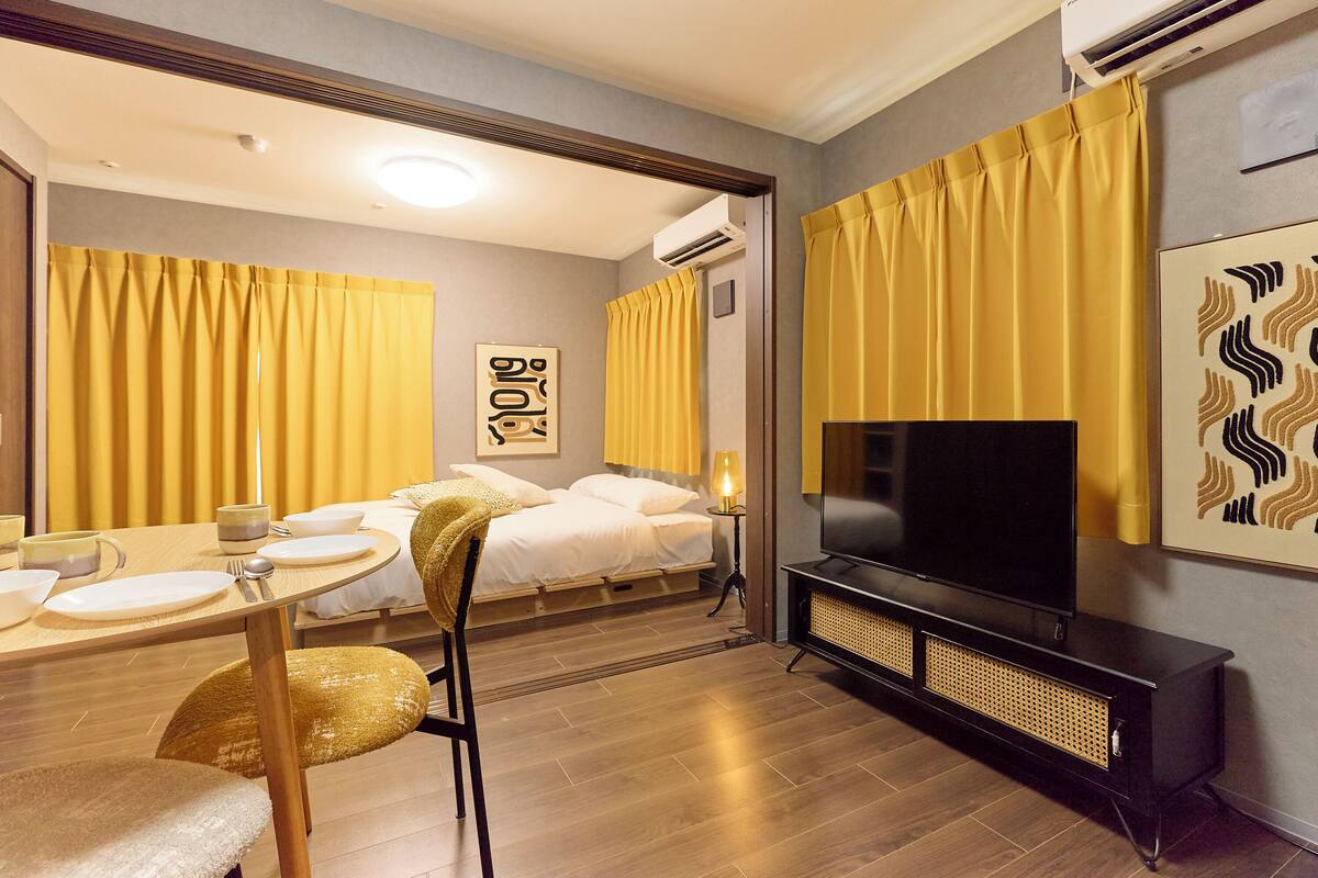 Une chambre d’hôtel comprenant un lit, une télévision, une table à manger avec des chaises et un miroir.