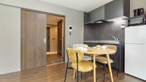 A modern kitchen with a dining table, chairs, and a microwave. - J-ARC Kamata (Ota-ku)