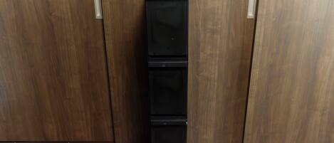 A black, three-tiered, wheeled storage unit against a wooden wall.