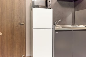 Eine kleine Küche mit Mikrowelle, Kühlschrank, Spüle und Schränken.