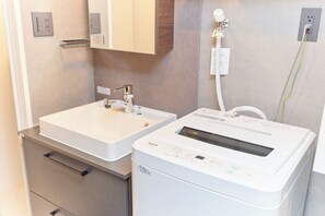 Une salle de bain équipée d’un lavabo, d’un miroir, d’un porte-serviettes et d’un lave-linge.