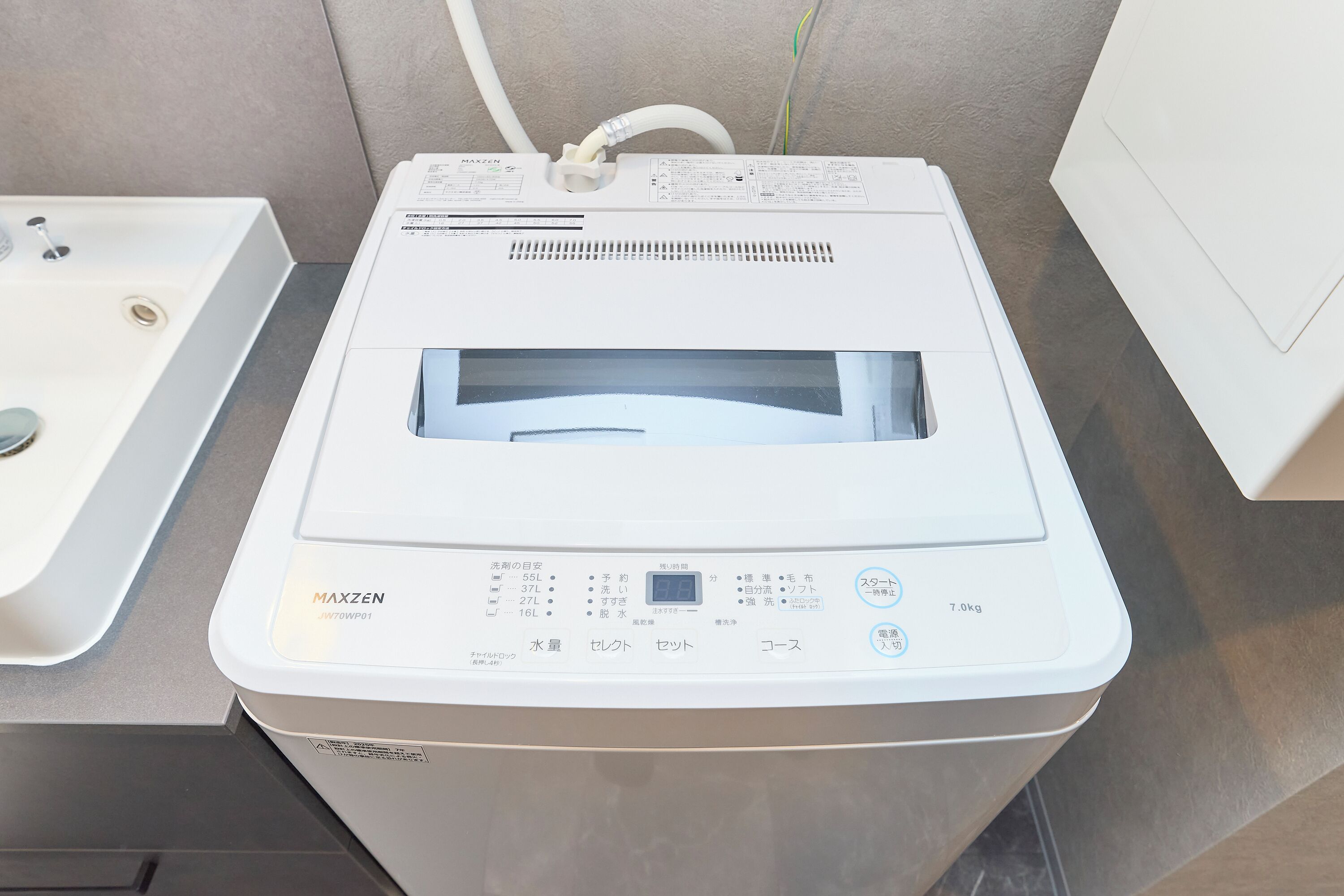 Máquina de lavar roupa branca com painel de controle, entrada de água e sistema de escoamento.