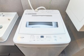 Eine weiße Waschmaschine mit Bedienfeld, Wasserzulauf und Ablauf.