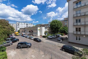 Ein Parkplatz mit Autos, ein Gebäude mit Balkonen und ein klarer Himmel.