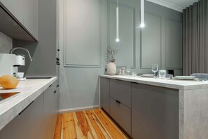 Eine moderne Küche mit Marmorarbeitsplatte, grauen Schränken und Holzboden.
