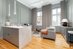 Ein modernes Wohnzimmer mit Kücheninsel, grauen Wänden, Holzböden und einem grauen Sofa.