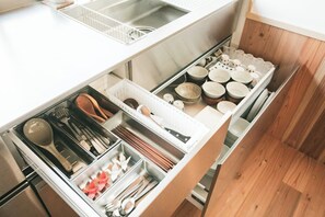 Eine Küche mit weißer Arbeitsplatte, einem Spülbecken und einem Schubladeneinsatz für Küchenutensilien und Schüsseln.