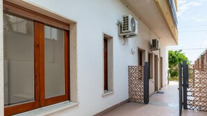 Un bâtiment doté de grandes fenêtres, de climatiseurs et d’un trottoir carrelé.