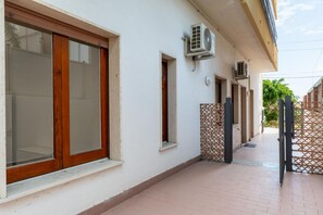 A building with large windows, air conditioning units, and a tiled walkway. - GuestHost - Casa degli Oleandri (Naxos)