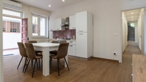 Une cuisine moderne avec des meubles blancs, une table à manger avec des chaises et un appareil de climatisation visible.