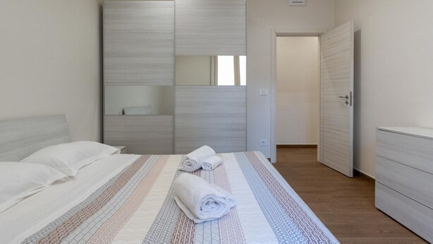 Une chambre à coucher comprenant un lit, une armoire et une porte donnant sur une autre pièce.