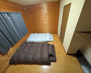 A small room with wooden walls, a bed with a grey and brown duvet, and a blue curtain. - Coco Stay 5minute walk from Kuroiso Station 2LD / Nasushiobara City Tochigi (Nasushiobara City)