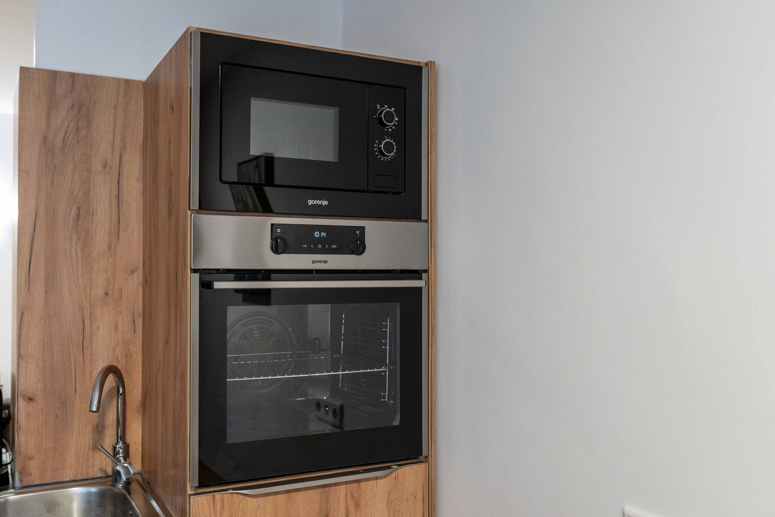 A kitchen with a microwave and oven built into a wooden cabinet.