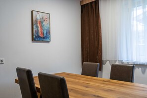 Un salón de conferencias con una mesa de madera y cuatro sillas, un cuadro en la pared y una ventana con cortinas.