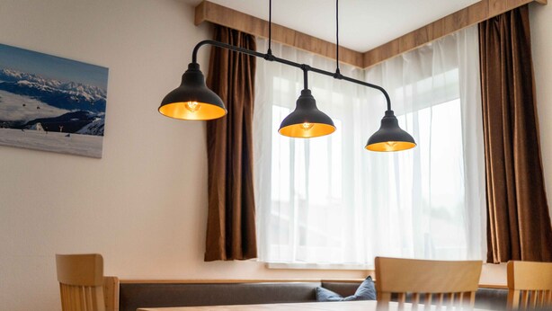 A dining area with a wooden table, two chairs, a bench, and a painting of a mountain landscape. - Maiskogelblick Apartments - TOP 9, Balcony & Sauna (Piesendorf)