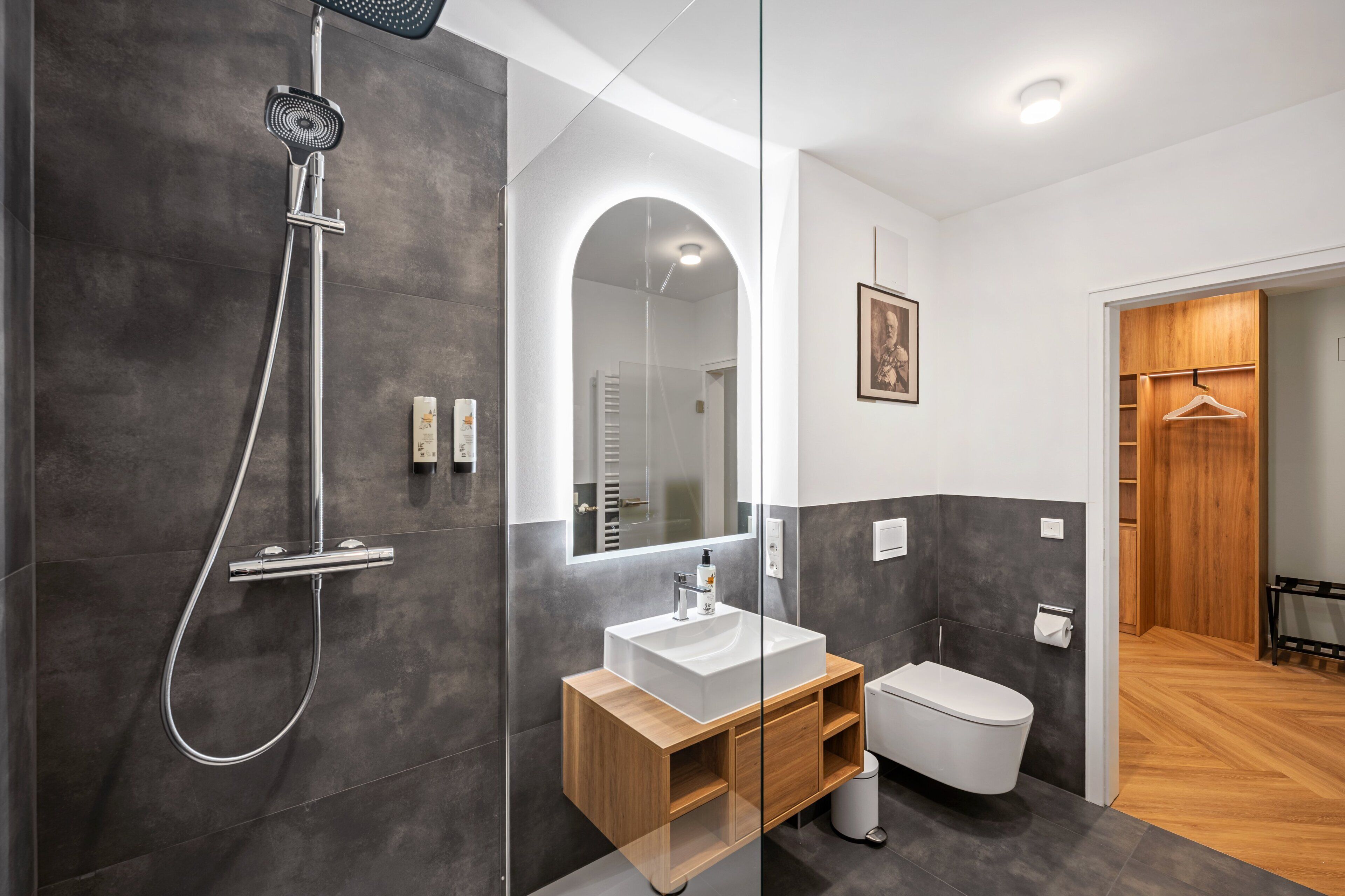 A modern bathroom with a shower, toilet, vanity, and a mirror.