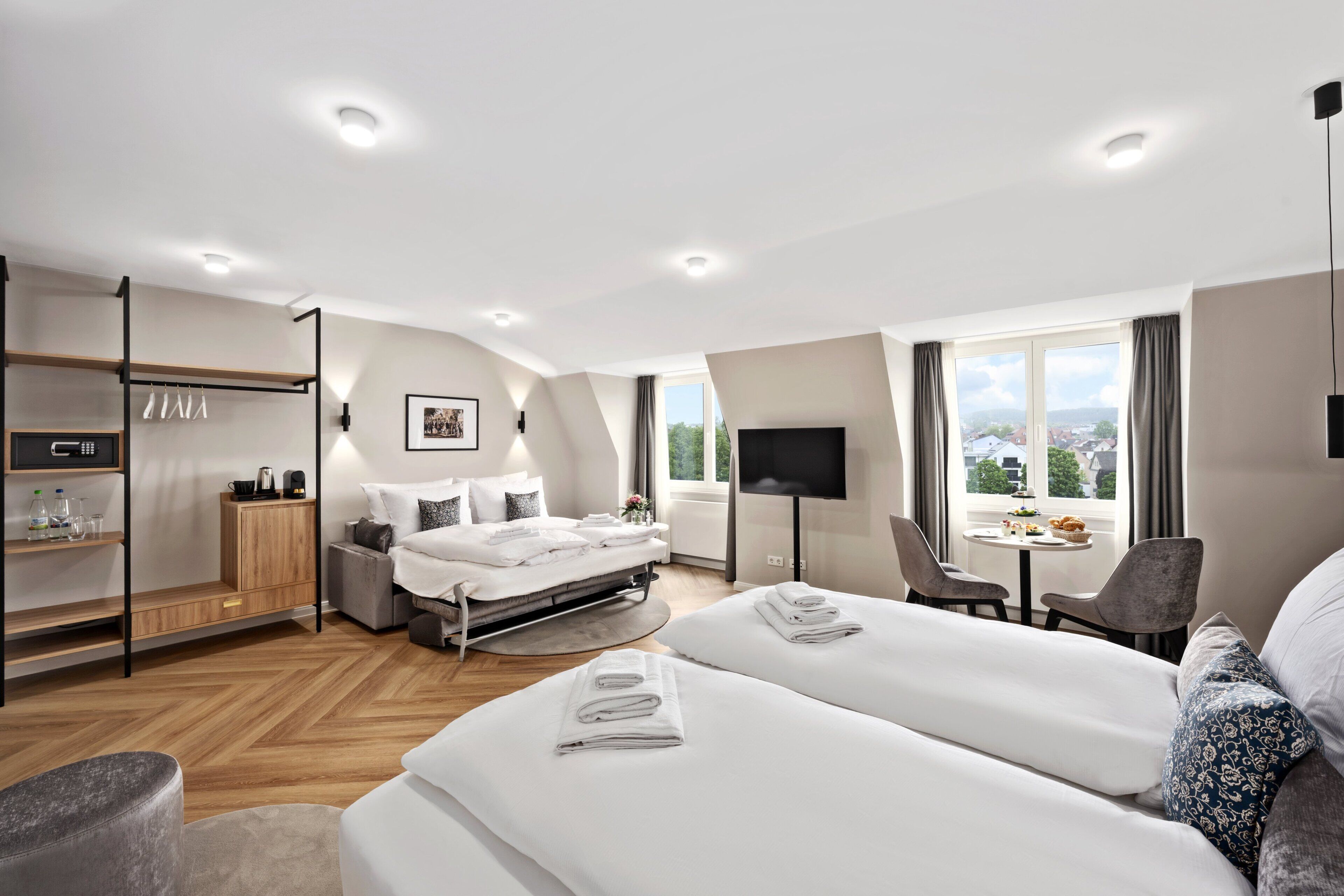 Ein modernes Hotelzimmer mit Bett, Schreibtisch, Fernseher und Blick auf die Stadt.