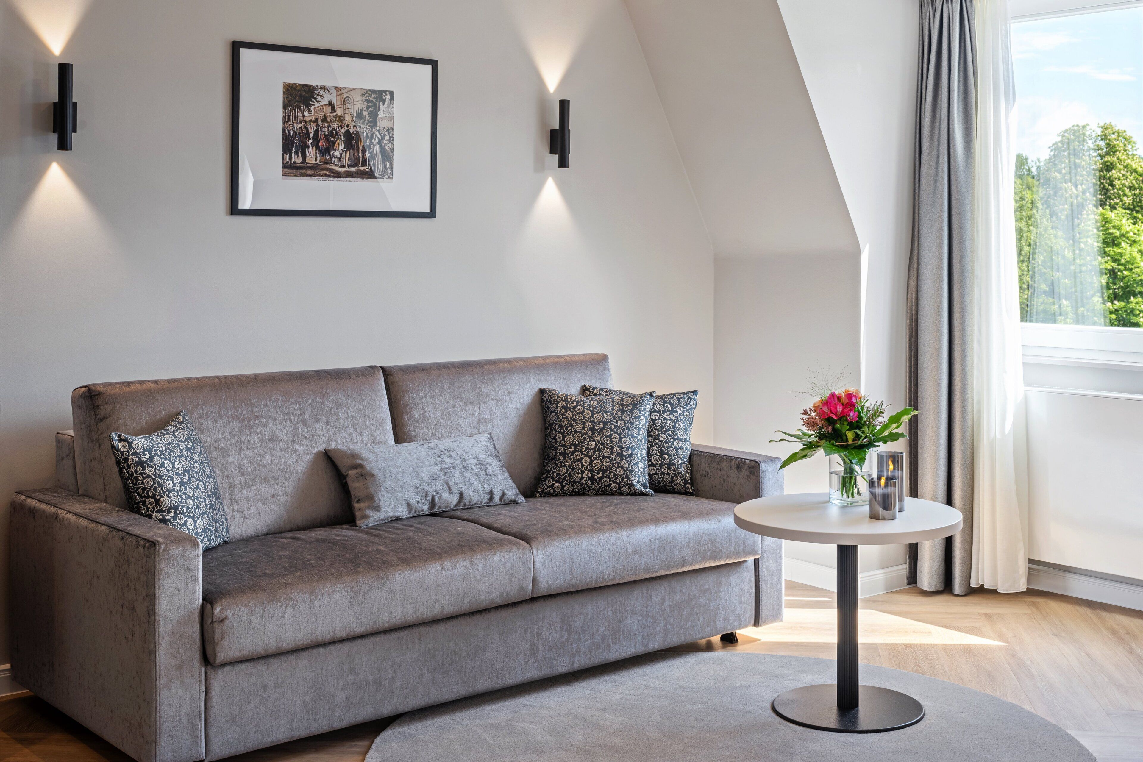 A modern living room with a grey sofa, a round coffee table, and a framed picture on the wall.