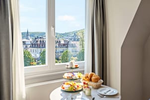 Una mesa de desayuno con pasteles, frutas y vista a un pueblo a través de una ventana.