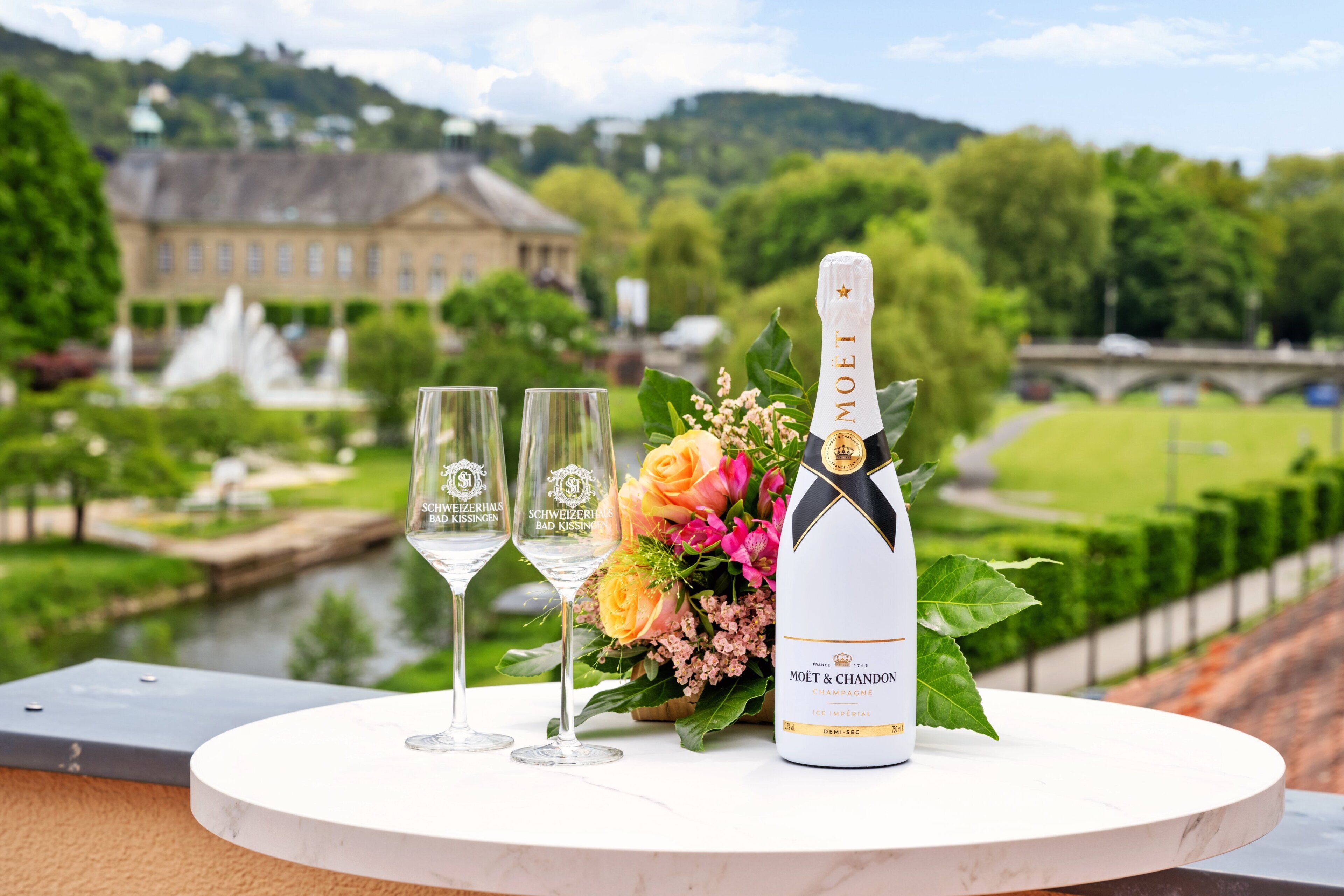 Une table avec deux verres, une bouteille de champagne Moët & Chandon et un arrangement floral.