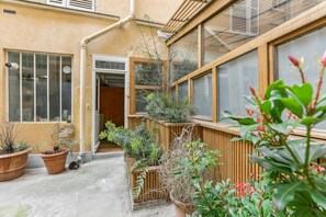 En boligbygning med en træbalkon, plantekasser og en dør ind til indgangen.