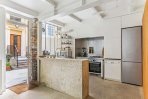 Una cocina moderna con una isla central, electrodomésticos de acero inoxidable y un pilar de ladrillo.