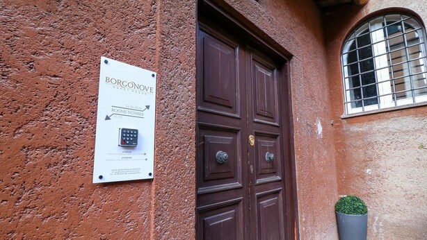 Eine Tür mit einem Schild, das 'BORGONOVE GUEST HOUSE' anzeigt, und einem Tastenfeld für den Zimmerzugang.