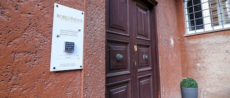 Puerta marrón con un letrero que indica 'BORGONOVE GUEST HOUSE' y un teclado para acceder a las habitaciones.