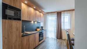 Een moderne keuken met houten kastjes, een zwarte kookplaat en een eethoek met een tafel en stoelen.