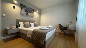 Ein modernes Schlafzimmer mit einem großen Bett, Nachttischen, einem Schreibtisch und einem Bild an der Wand.