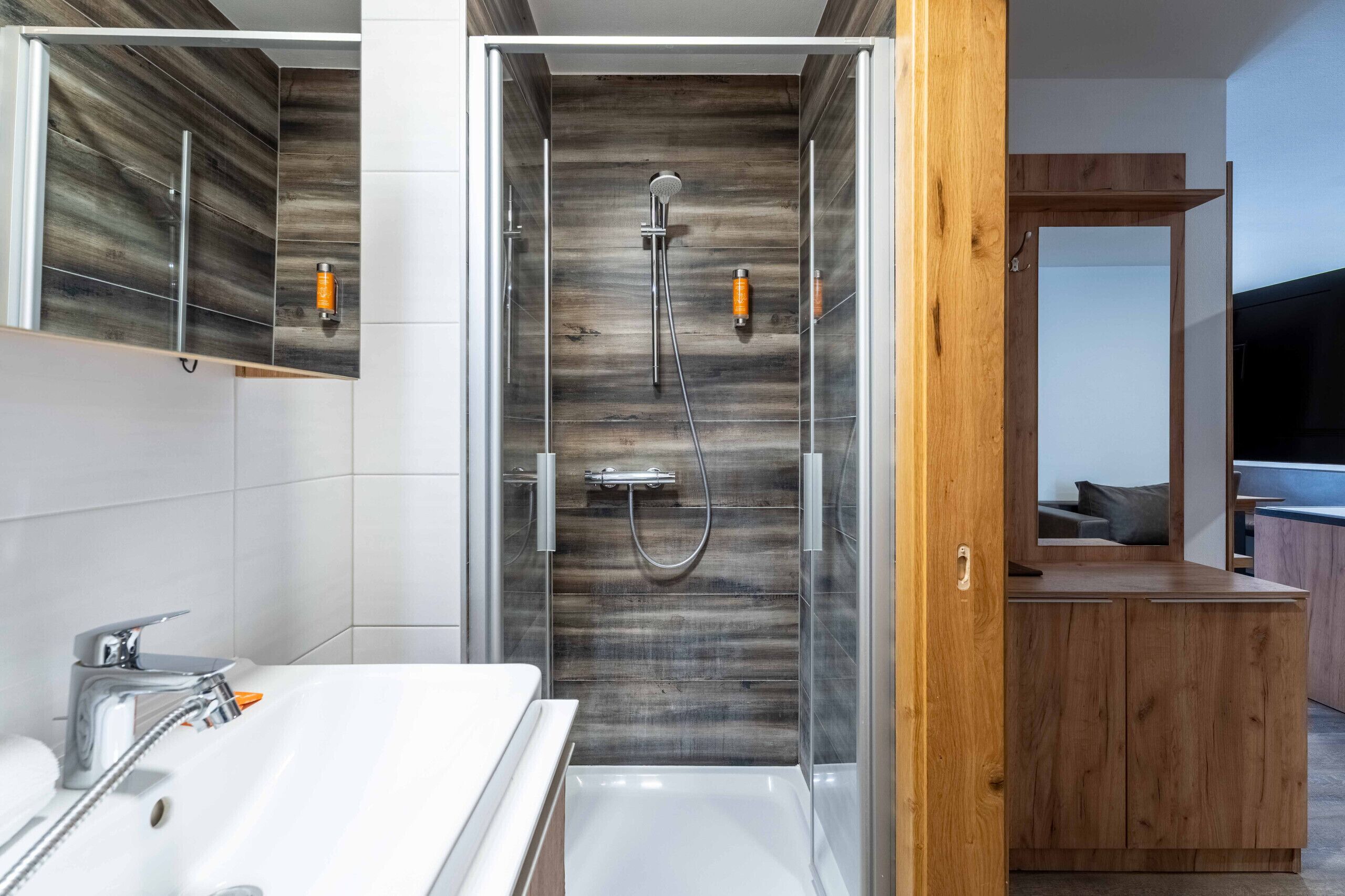Une salle de bain moderne avec une douche à parois de verre, une baignoire blanche et un meuble-lavabo en bois.