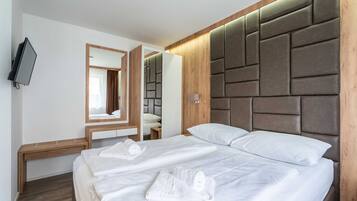 Une chambre d’hôtel avec deux lits, une tête de lit en bois, un téléviseur à écran plat et un miroir.