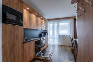 Eine moderne Küche mit Holzschränken, einem eingebauten Backofen und einer Mikrowelle.