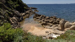 Eine zerklüftete Küstenlinie mit klarem Wasser, Vegetation und weit entfernten Landformen.